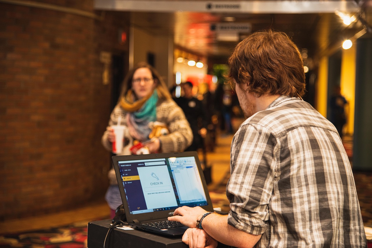 indoors, movie theatre, ticket, ticket check-in, customer, lobby, theatre, movie, computer, scanner, brown computer, brown laptop, brown movie, brown theater, brown check