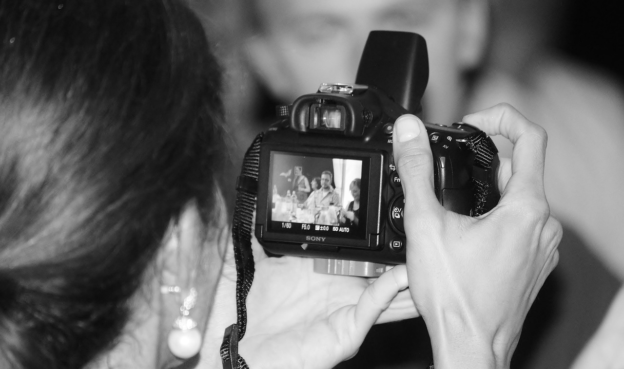 لقطة مقربة ليد مصور تحمل كاميرا رقمية احترافية، تلتقط لحظات من حفل زفاف، مما يعكس جوهر التصوير الفوتوغرافي الرقمي في حفلات الزفاف.